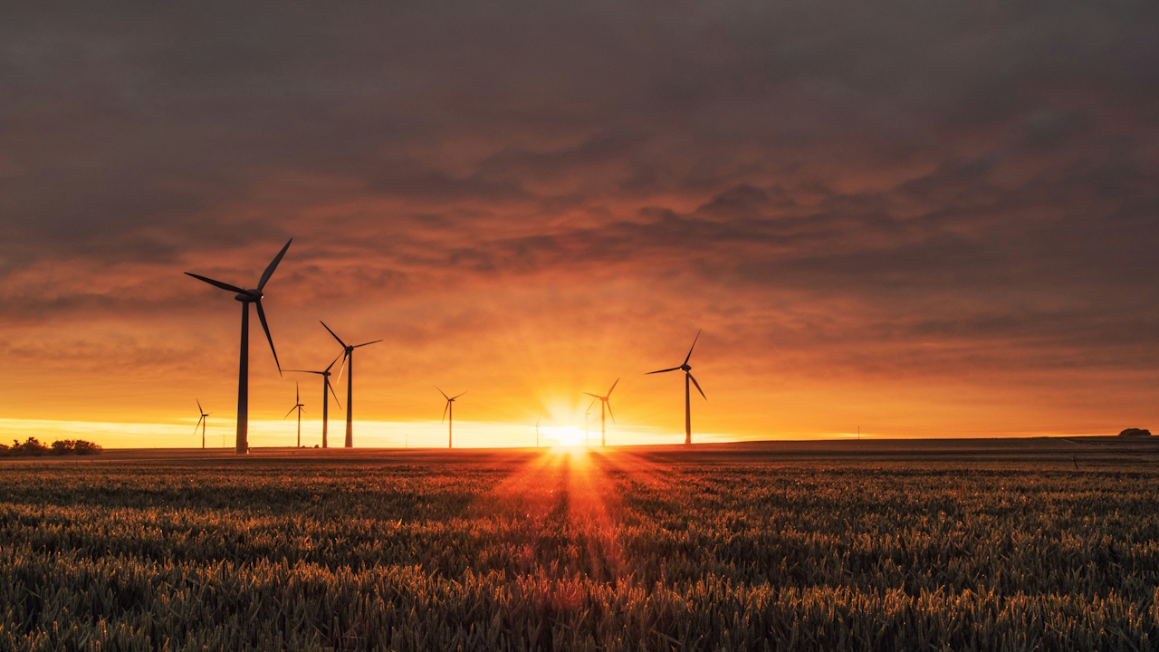 Windkraftanlagen auf einem Feld im Sonnenuntergang.