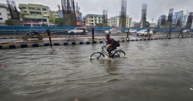 Mann fährt mit Fahrrad durch Wasser auf einer überfluteten Straße.